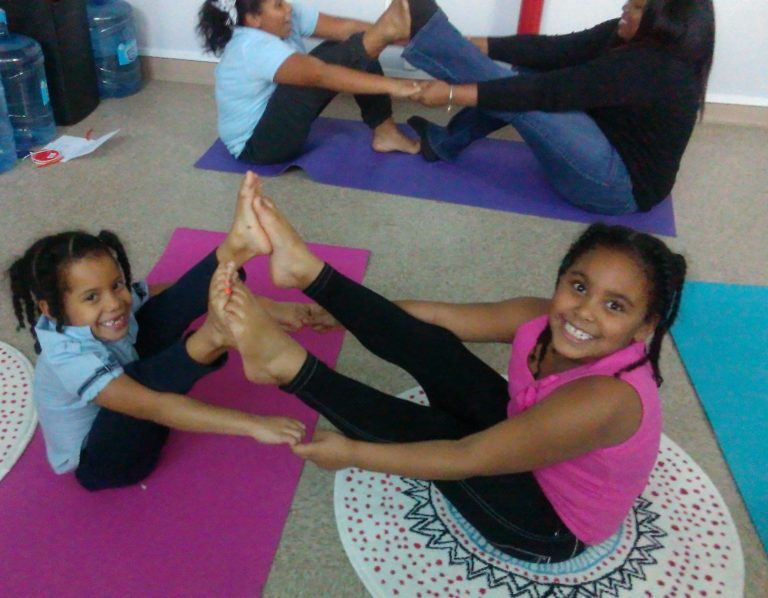 Woman in a blue outfit meditating in a serene indoor setting.